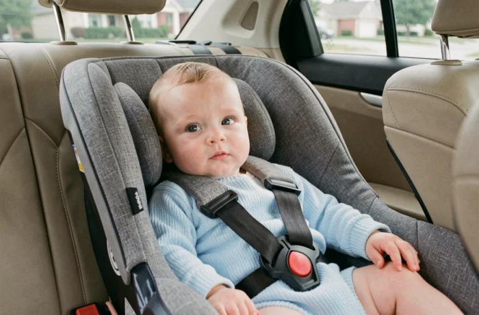 Bebê de quatro meses instalado em um bebê conforto sem redutor em um assento de carro de família